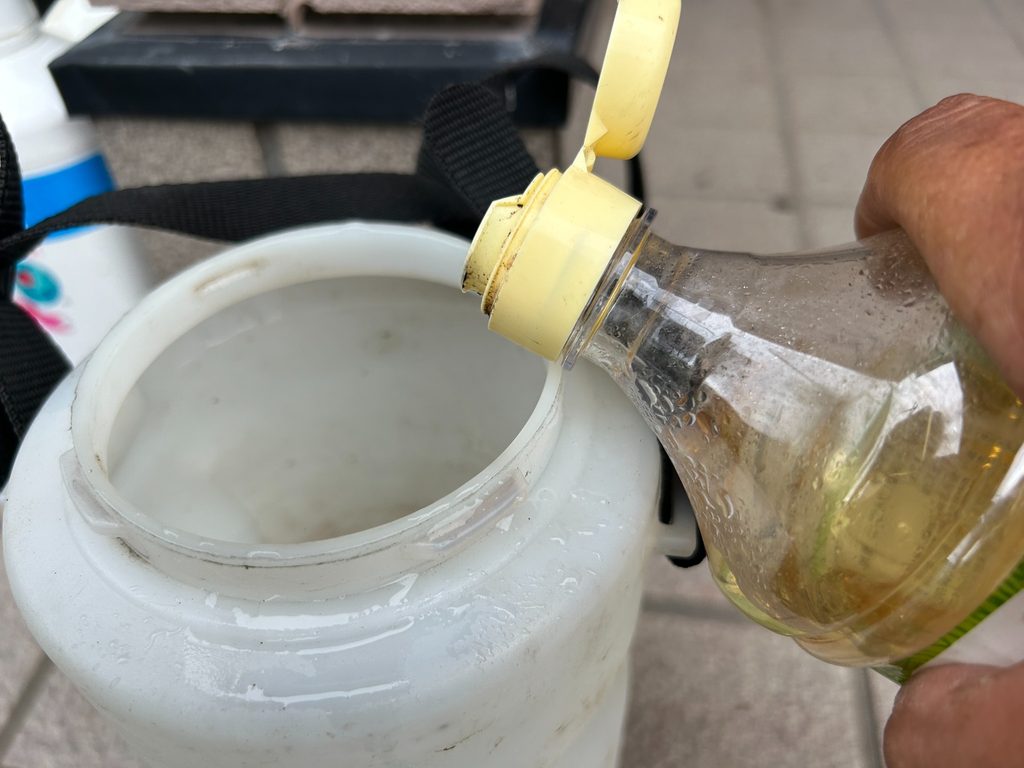 2026年8月18日のおーしん菜園で穀物酢を噴霧器のタンクへ入れてお酢スプレーを調整している様子